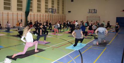 Grupa osób ćwiczy jogę w sali gimnastycznej