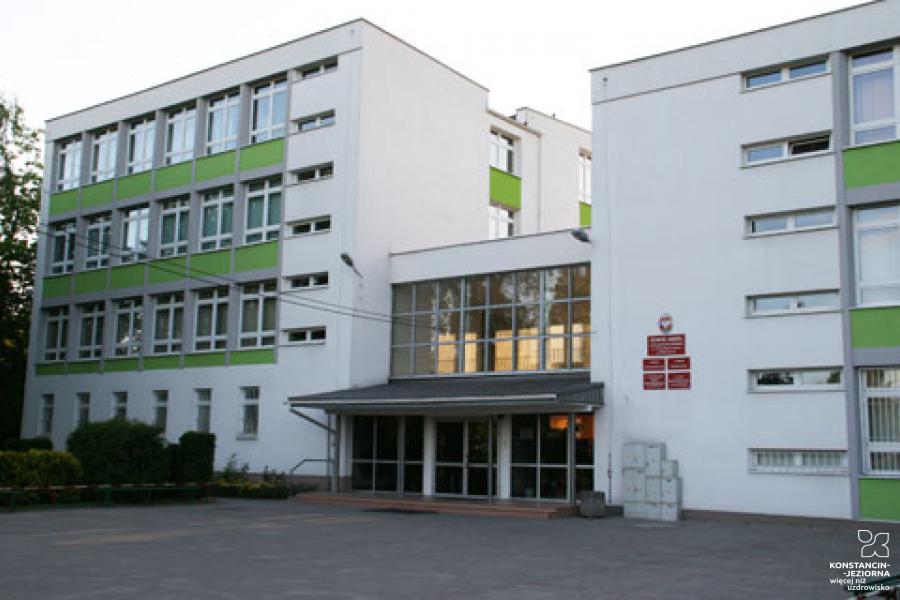 Wielopiętrowy budynek z biało-zieloną elewacją, dużą liczbą okien i płaskim dachem.