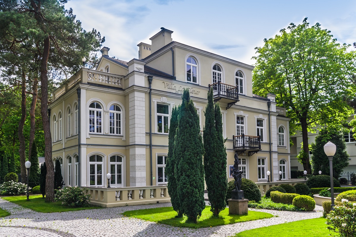 Wiosenny widok na willę le Fleur oraz towarzyszący jej stylizowany ogród ze strzyżonymi roślinami