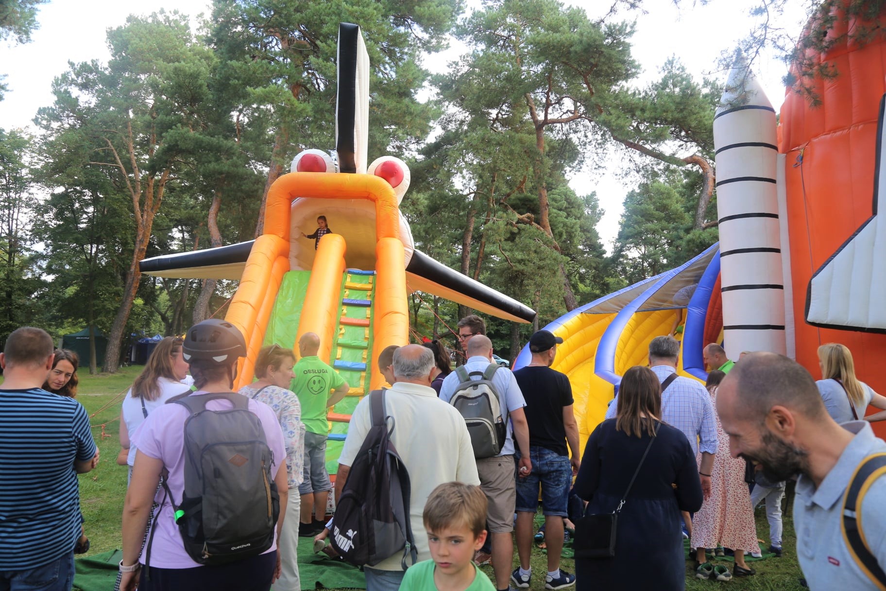 Park Zdrojowy. Dwie duże dmuchane zabawki ze zjeżdżalniami. Na nich bawią się dzieci. Przed zabawkami stoją osoby dorosłe.