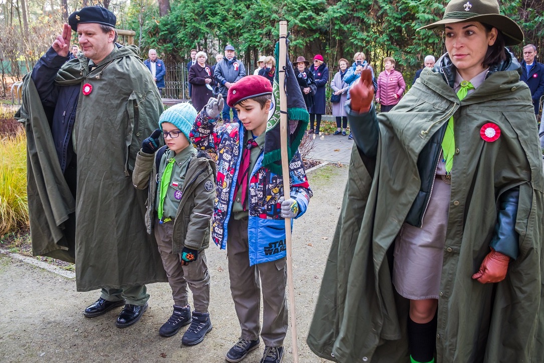 Kobieta, mężczyzna i dwóch chłopców w wieku szkolnym stoją obok siebie w rzędzie. Ubrani są w stroje harcerskie. Na głowach mają berety.