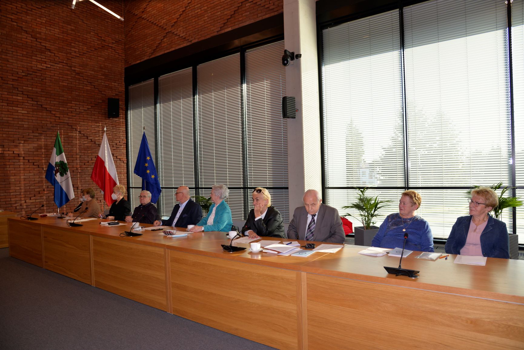 Sala posiedzeń. Przy drewnianym stole siedzi dziesięć osób. Siedem kobiet i trzech mężczyzn, seniorzy. 