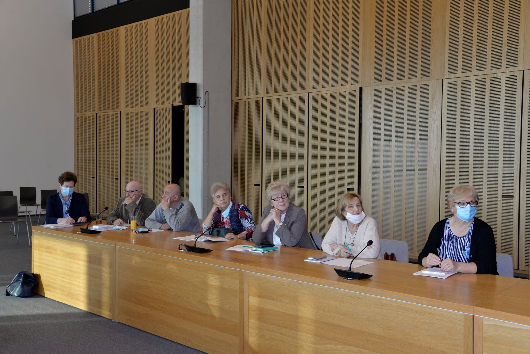 Sala posiedzeń. Przy drewnianym stole siedzi siedem osób. Pięć kobiet i dwóch mężczyzn, seniorzy.