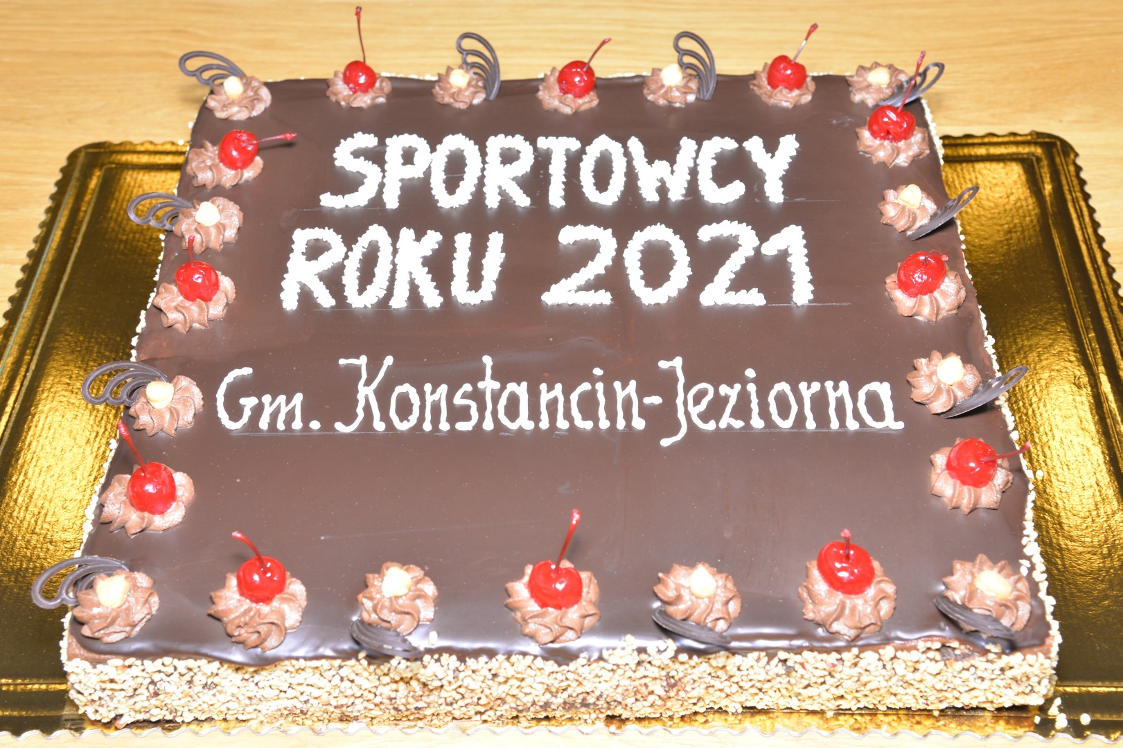 Tort czekoladowy w kształcie prostokąta, na środku napis: Sportowcy roku 2021 gm. Konstancin-Jeziorna.
