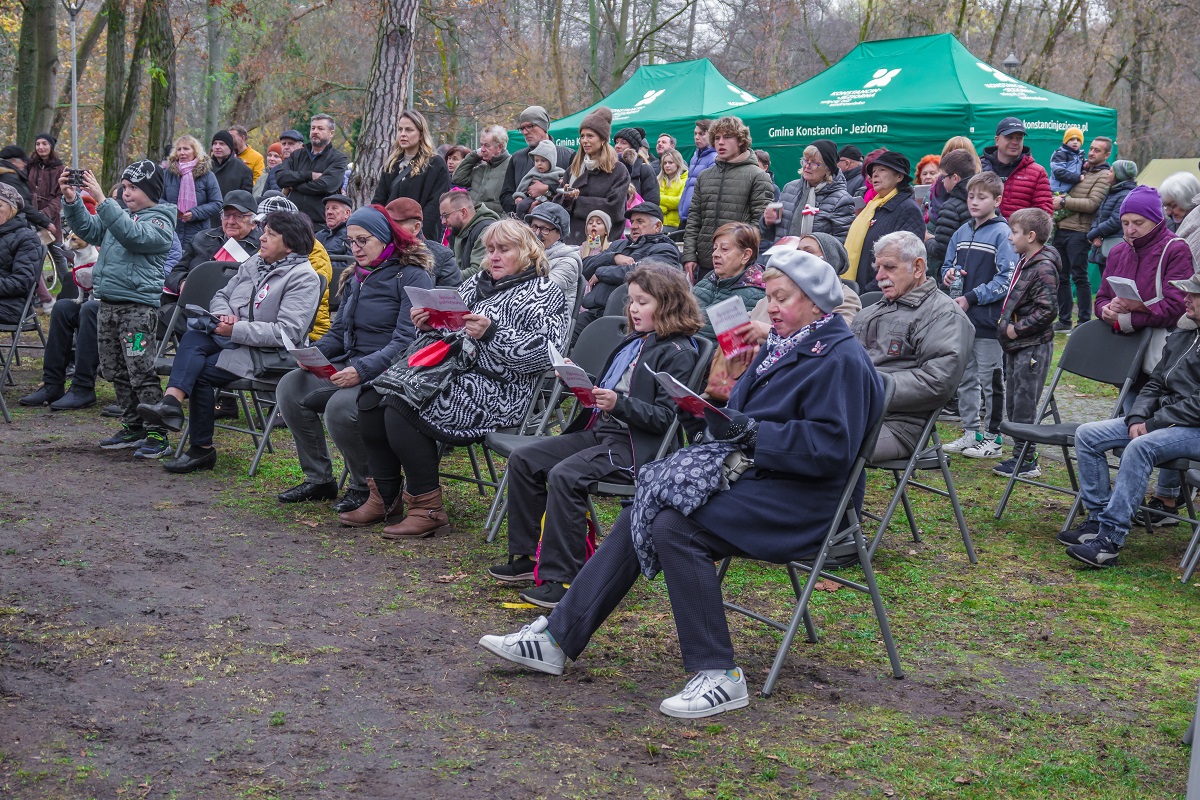6.	Ludzie siedzą na krzesełkach i stoją na trawniku. Trzymają śpiewniki i śpiewają.