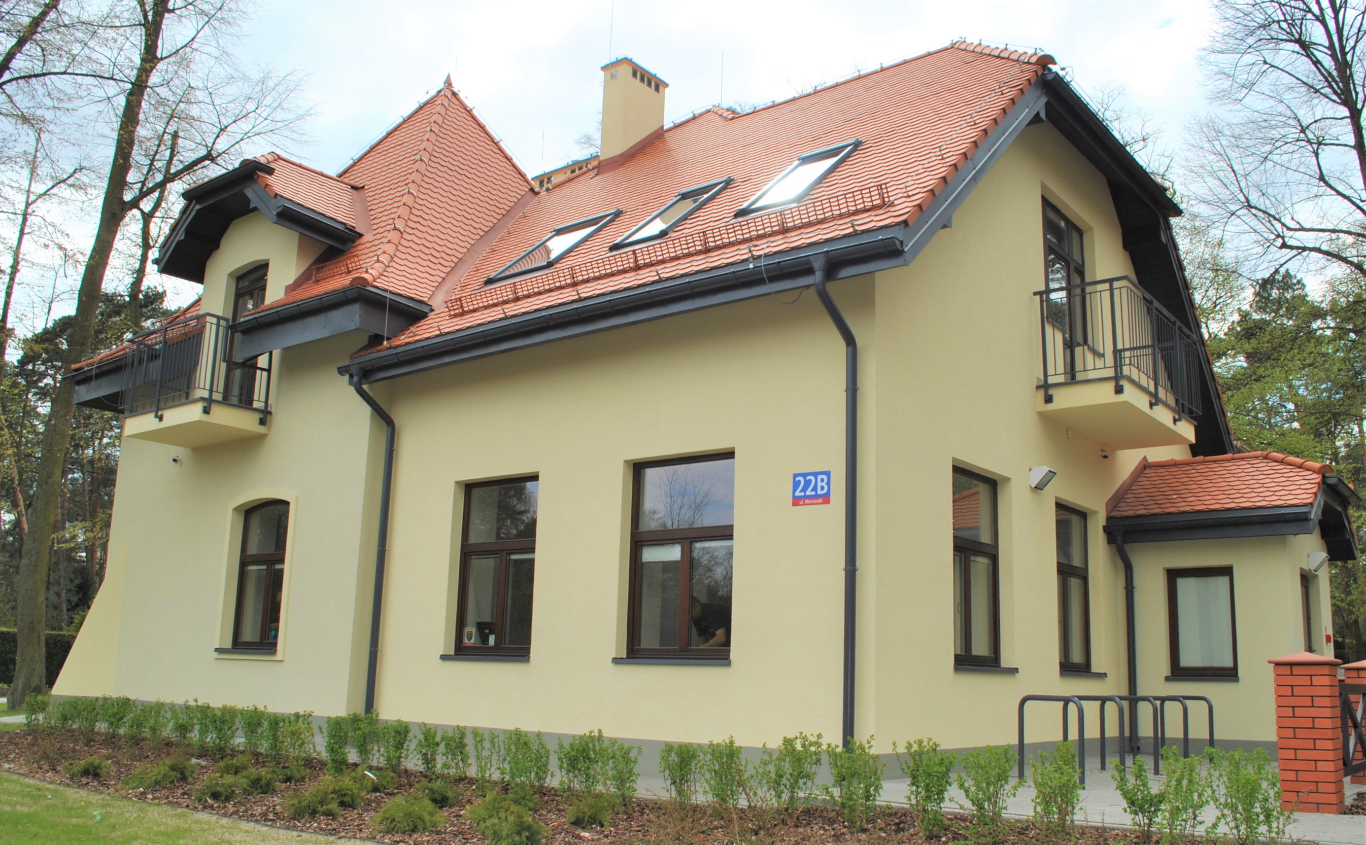 Duży piętrowy budynek  ze spadzisty dachem pokrtytm czerwoną blachodachówką 