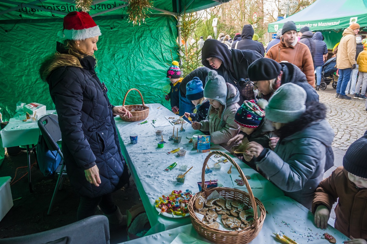 Uśmiechnięte dzieci uczestniczą w warsztatach świątecznych, dekorując pierniczki i tworząc ozdoby choinkowe.