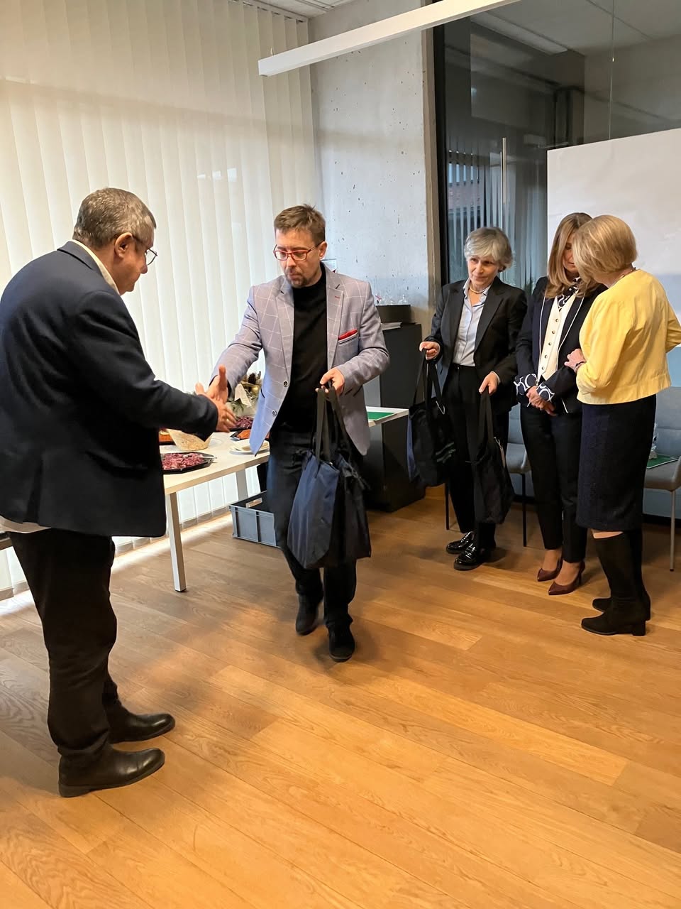 Grupa osób stoi w sali urzędu podczas świątecznego spotkania, w trakcie którego wręczane są podziękowania członkom Rady Seniorów.