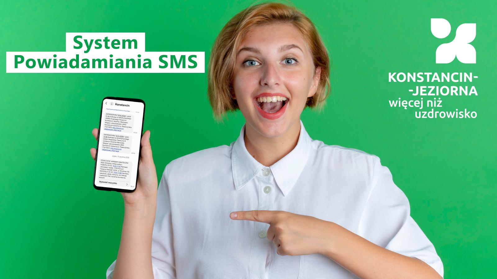 Młoda kobieta z szerokim uśmiechem trzyma w dłoni smartfon z wiadomościami SMS, na zielonym tle z napisami promującymi system powiadamiania SMS dla Konstancina-Jeziorny.