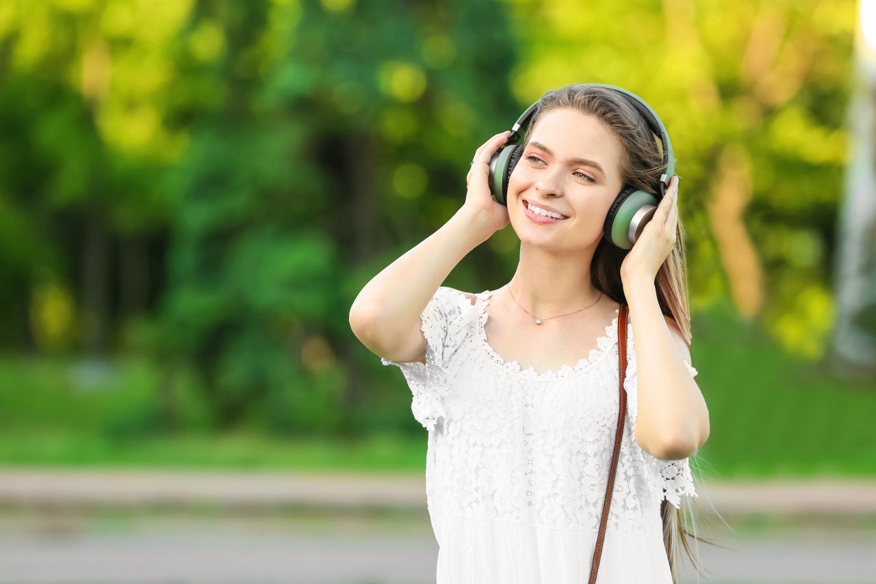 Smiling young woman with headphones over her ears outdoors 