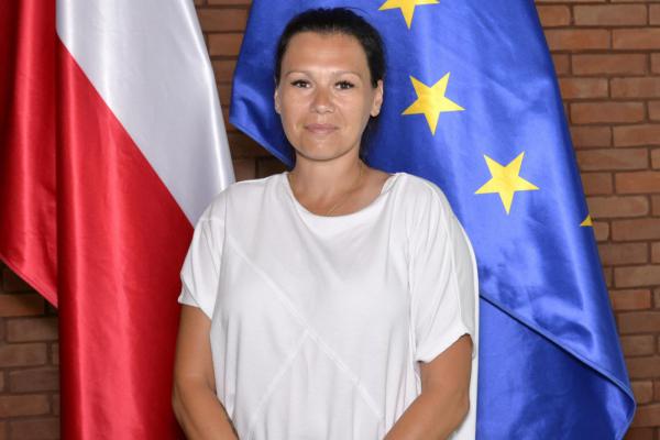 Zdjęcie portretowe kobiety – ciemne upięte włosy, ubrana jest białą bluzkę.