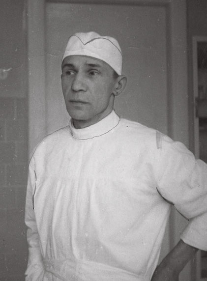 Czarno-biała fotografia przedstawiająca Adama Grucę, ubranego w  szpitalny uniform, na głowie ma czepek. 