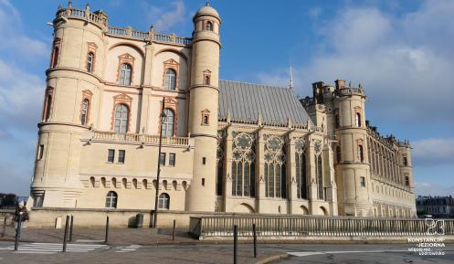 Duży kamienny zamek o renesansowej architekturze bryły z elementami gotyku, przed zamkiem ulica