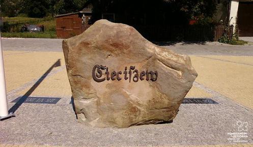 Duży brązowy kamień, na którym umieszczony jest napis – Cieciszew. Kamień stoi na placu z kostki