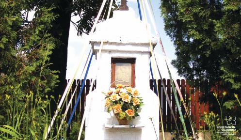 Przydrożna mała kapliczka – murowana, pomalowana na biało, na środku znajduje się obraz Matki Boskiej, na górze stoi duży metalowy krzyż. Kapliczka jest ogrodzona. Wokół rosną kwiatki. 