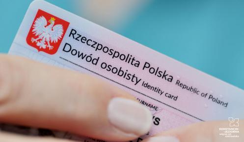 Fragment dowodu osobistego, który w palcach trzyma kobieta. Widoczna jest tylko jej dłoń. 