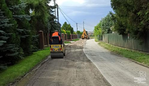 Remont ulicy. Z lewej strony zdjęty jest już asfalt, po prawej jeszcze nie. W tle widać walec oraz koparki. 