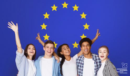 Grupa uśmiechniętych uczniów (5 osób, w tym trzy kobiety) na tle flagi Unii Europejskiej (okrąg złożony z dwunastu złotych gwiazd na błękitnym tle).