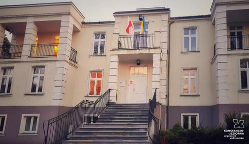 Budynek, na pierwszym planie schody, na którym są wywieszone flagi Polski i Ukrainy.