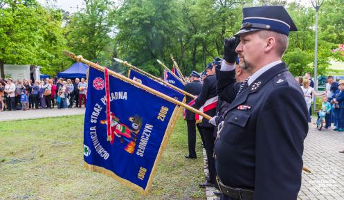 Strażacy trzymający sztandar z napisem Ochotnicza Straż Pożarna Słomczyn. 