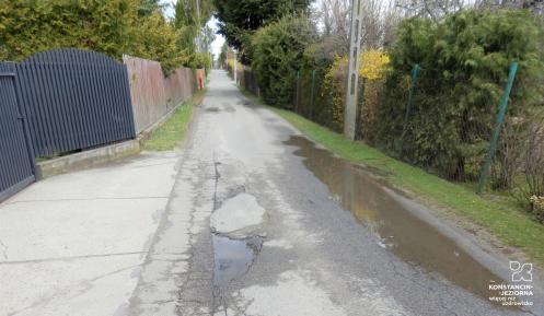 Ulica asfaltowa, po lewej stronie widoczne są dziury w drodze. 