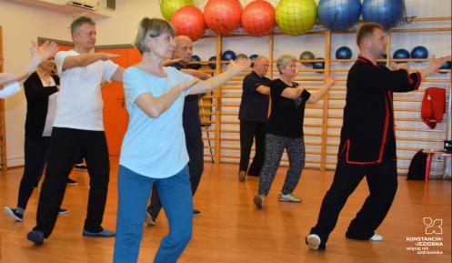 Grupa osób (seniorów) ćwiczy na sali fitness.