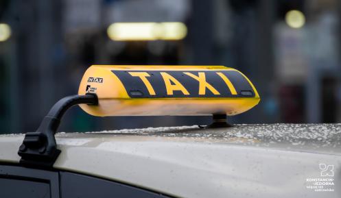 zdjęcie dachu białego samochodu z żółtym wyświetlaczem taxi 