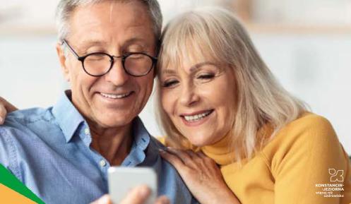 Para seniorów: kobieta i mężczyzna patrzą razem na ekran telefonu