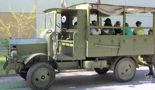 Stary wojskowy zabytkowy samochód, na którego pace siedzą uczniowie