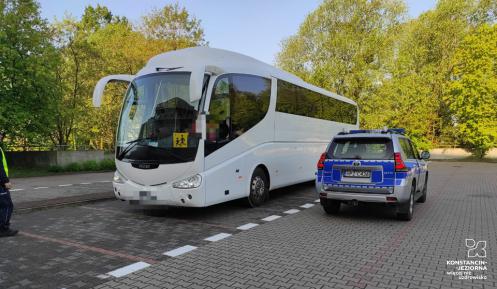 Autokar i wóz policyjny stoją na chodniku. 