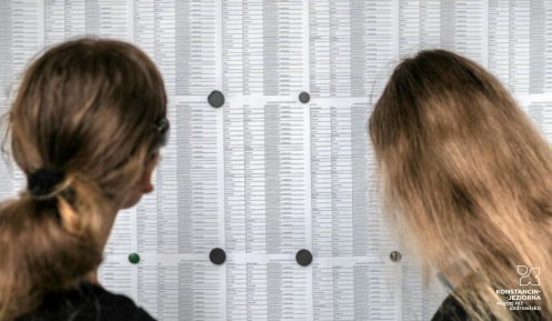 Dwie dziewczynki patrzą ta tablice, na której wywieszone jest wyniki egzaminów. 