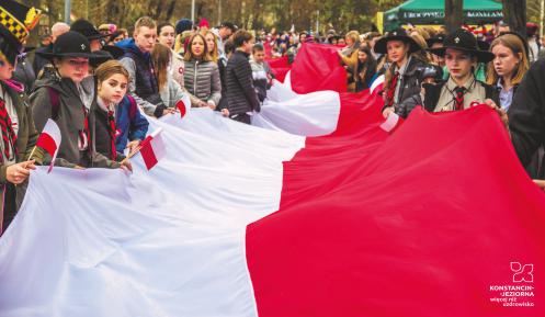 Grupa osób niesie gigantyczną biało-czerwoną flagę.