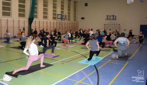 Grupa osób ćwiczy jogę w sali gimnastycznej