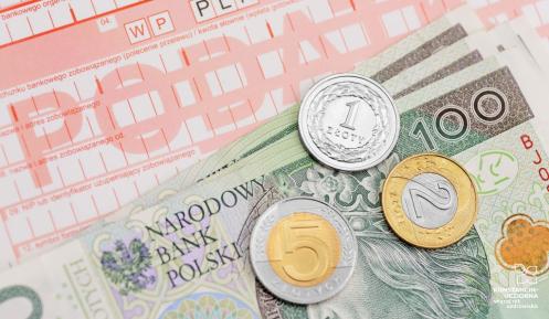 Druk przelewu podatku, na którym leżą banknoty i monety o różnych nominałach.