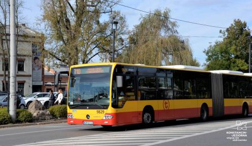 Ulica, po której jedzie czerwono-pomarańczowy autobus komunikacji miejskiej