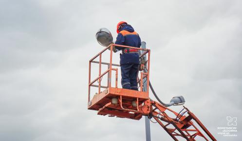 Elektryk naprawiający latarnię uliczną na wysokości.