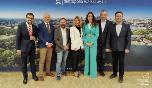 Grupa osób na tle ścianki promocyjnej z napisem metropolia warszawska 
