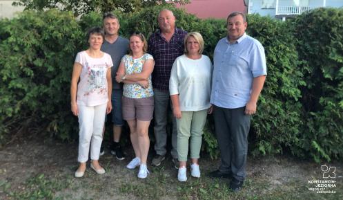 grupka osób stoi na tle krzaków 