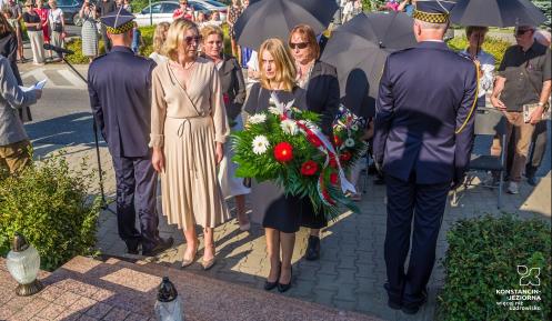 Dwie osoby składające kwiaty na pomniku