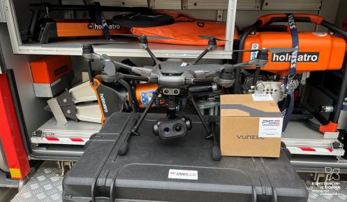 Dron z kamerą nad polaną, w tle drzewa