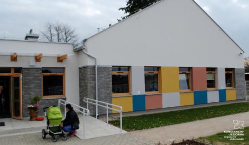 budynek z kolorowymi namalowanymi kwadratami, przed budynkiem kobieta z wózkiem