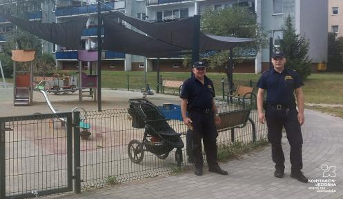 Dwóch mężczyzn w mundurach w tle plac zabaw i bawiące się dzieci.