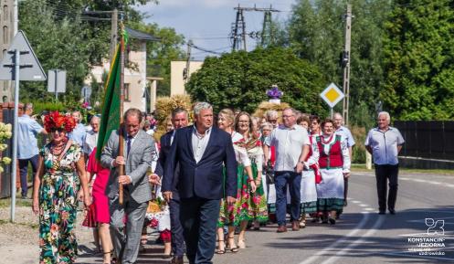Grupa osób maszerująca środkiem drogi.