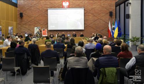 Sala posiedzeń wypełniona osobami siedzącymi na krzesełkach