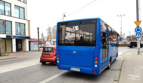 Niebieski autobus stoi na przystanku, w tle ulica z samochodami.