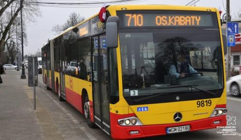 Żółto-czerwony autobus linii 710 komunikacji miejskiej, stojący na przystanku z widocznym kierunkiem Os. Kabaty.