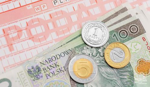 Banknoty i monety leżące na druku pocztowym.