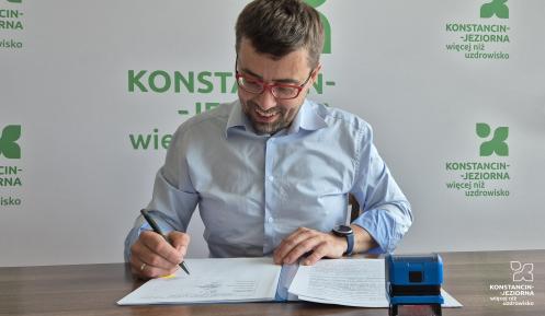 Uśmiechnięty mężczyzna podpisuje dokumenty.