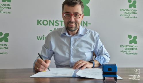 Uśmiechnięty mężczyzna podpisuje dokumenty.