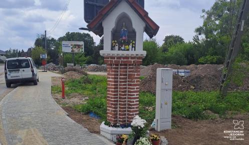 Przydrożna kapliczka przy chodniku.